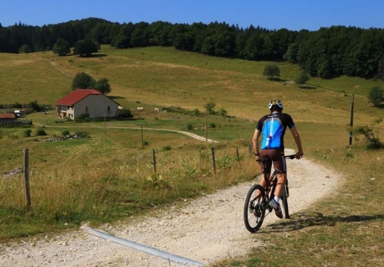 Un vététiste sur un chemin du plateau de Retord en été