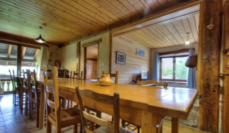 The gîte dining room with its large wooden table and beams
