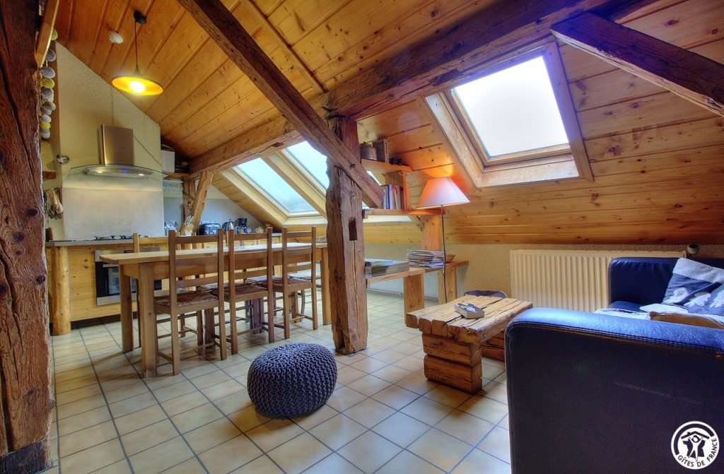 Living room of the group gîte, under the beams and roof windows, with its large wooden table and lounge area
