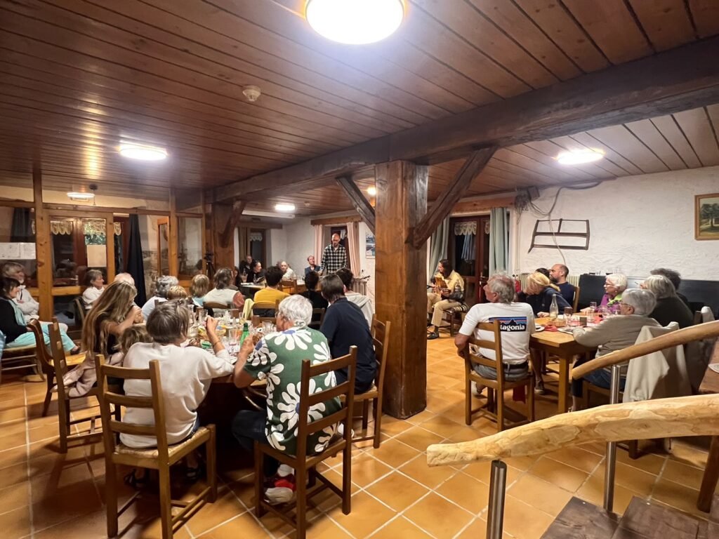 Repas en tablée dans la salle de l’auberge, sous les poutres