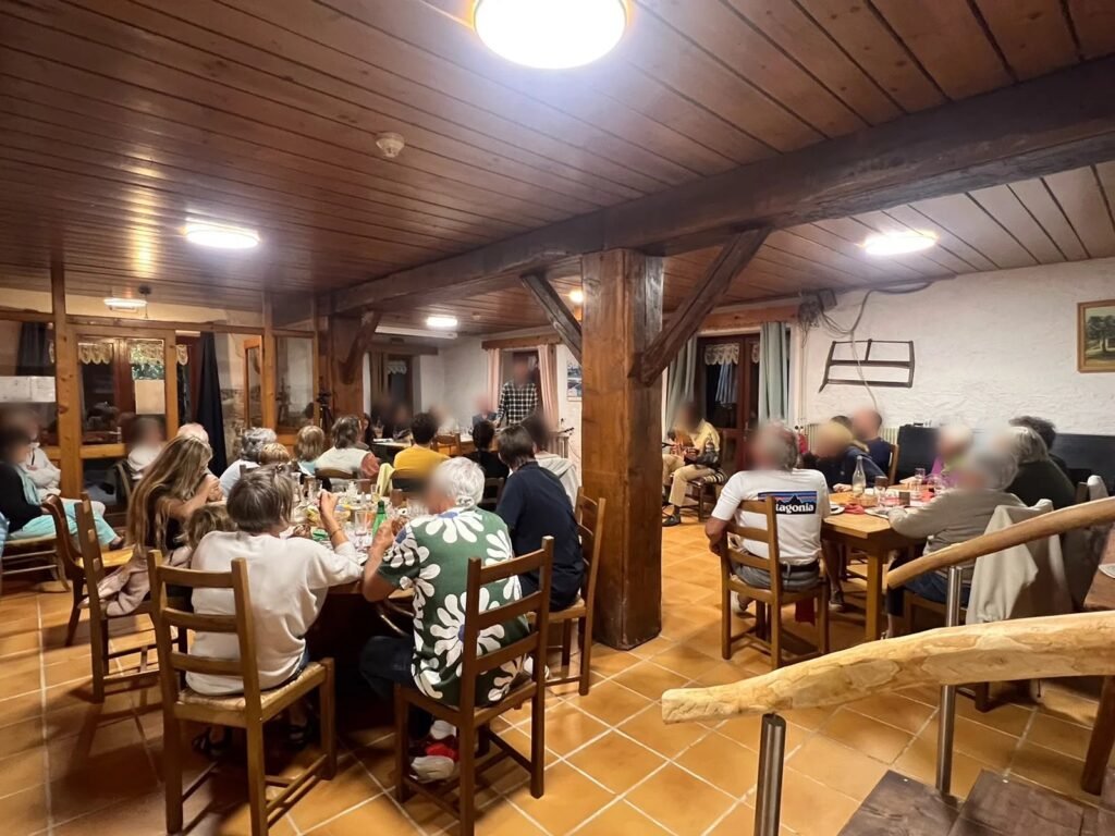 The dining room of the Grange des Plans farm inn, with its beams and wooden tables, during a meal
